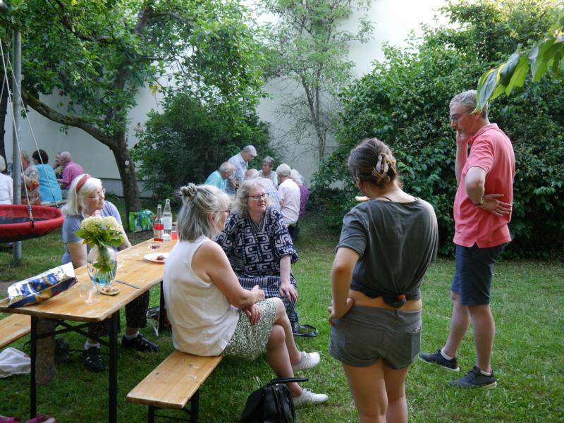 Ehrenamtliche in unterhalten sich im Pfarrgarten.